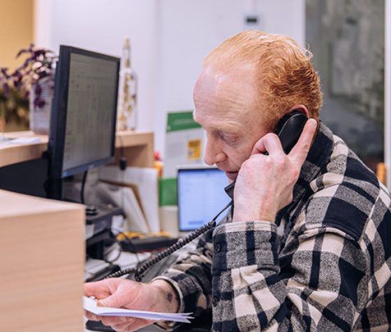 man met geruite bloes telefoneert