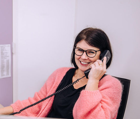 lachende vrouw met bril telefoneert