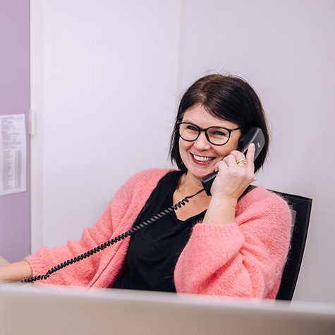 lachende vrouw met bril telefoneert