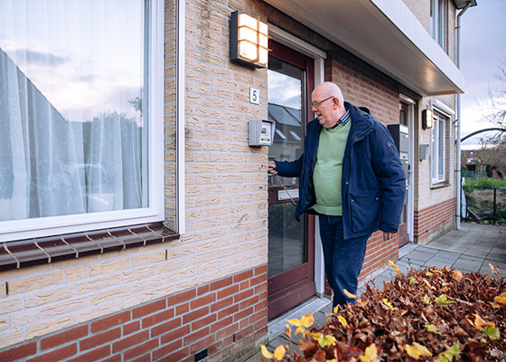 oudere man opent zijn voordeur