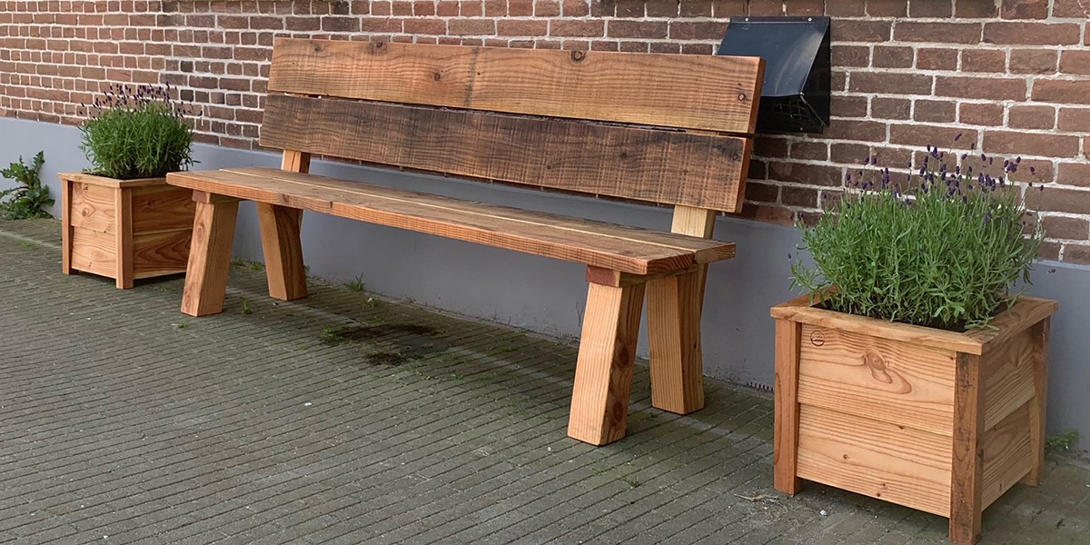 een robuuste houten tuinbank met aan elke kant een houten plantenbak met een lavendelplant